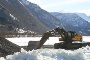 Gravemaskin Volvo EC 380i arbeid om vinteren med fjell i bakgrunnen