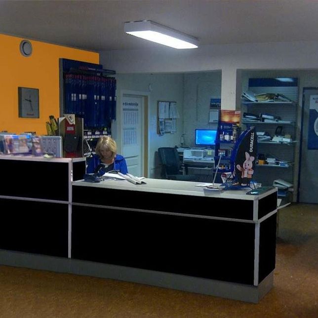 Dame sitter bak resepsjon klar for kundemottak 