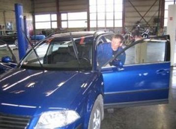 Mann på verksted setter seg inn i en blå bil