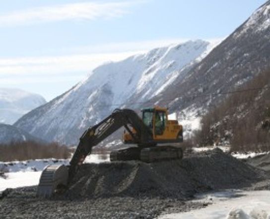 Gravemaskin Volvo EC 210 B står på toppen av en haug av grus