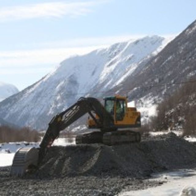 Gravemaskin Volvo EC 210 B står på toppen av en haug av grus
